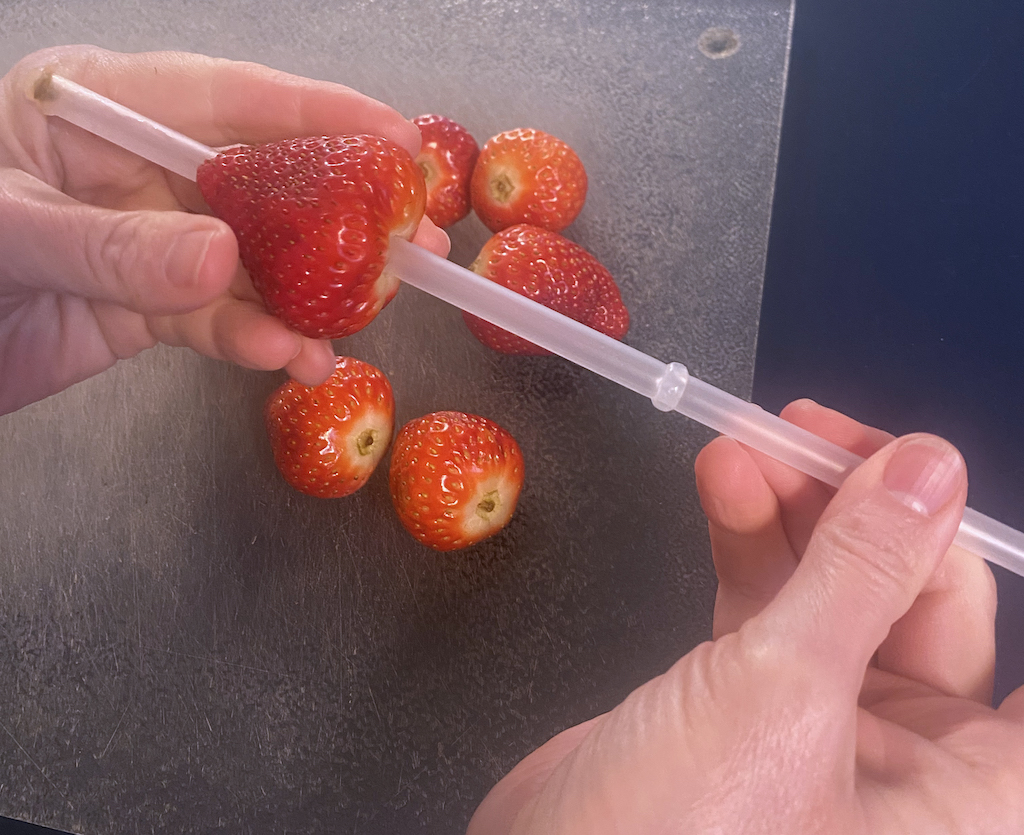 carefully push the straw from over the stem all the way through the berry